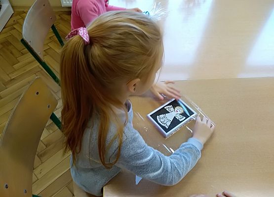 Dziewczynka owija folią obrazek