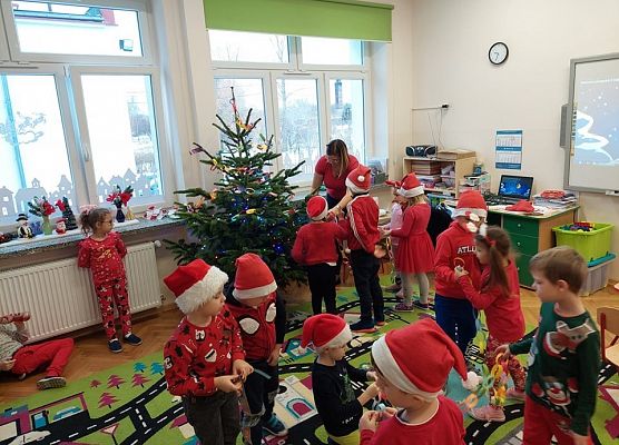dzieci wraz z nauczycielką ubierają choinkę
