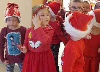 Dzieci w świątecznych strojach stoją przed stołówką