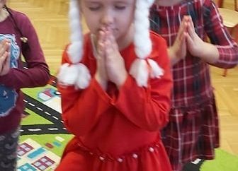 Dwie dziewczynki w mikołajkowych strojach stoją na jednej nodze