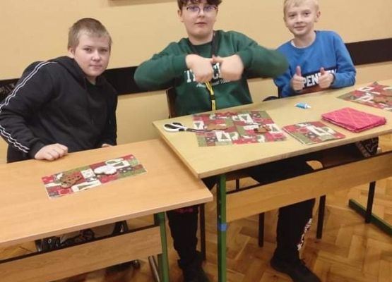 Chłopcy siedzą w ławce i wykonują świąteczne kartki