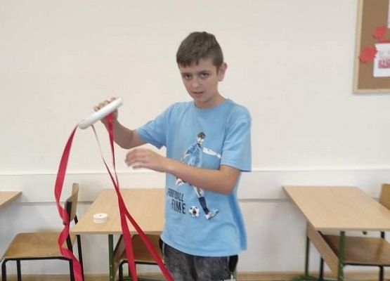 Uczeń zawija wstążkę na stroiku