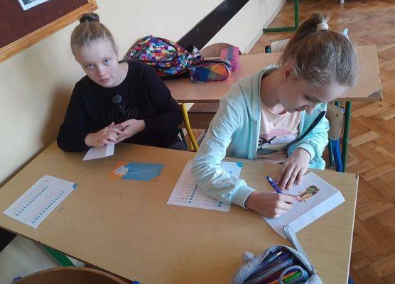 Uczennice wkładają do kopert ankietę