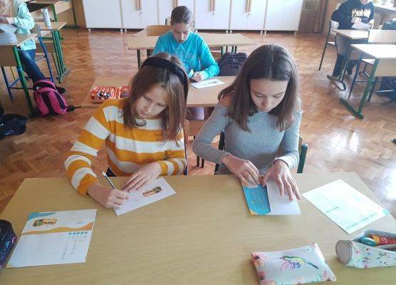 Uczennice wkładają do kopert ankietę