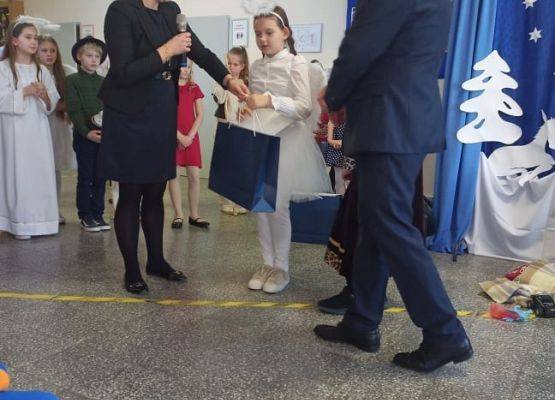 Dyrektor i pedagog wręczają nagrodę uczestnikowi konkursu