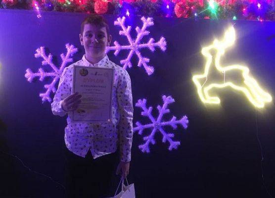 Uczestnik konkursu stoi i pokazuje dyplom