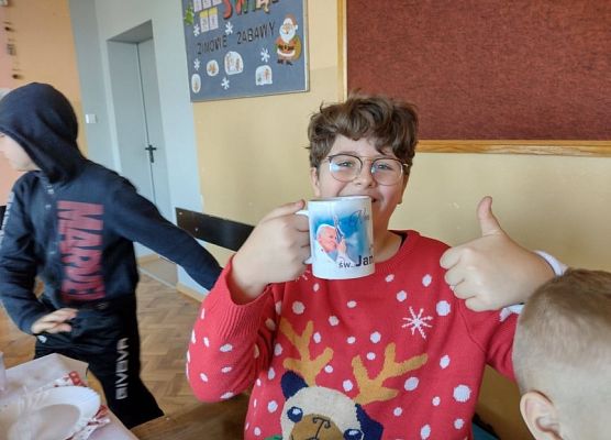 Uczeń z uśmiechem na twarzy pokazuje swój prezent