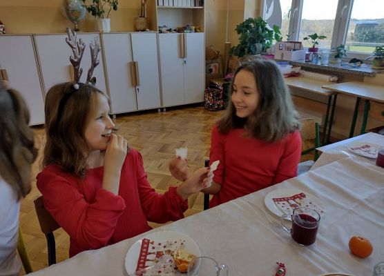 Uczennice dzielą się opłatkiem i składają sobie życzenia