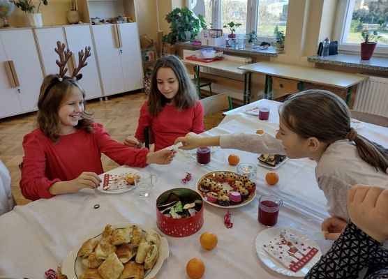 Uczennice siedza przy wigilijnym stole.