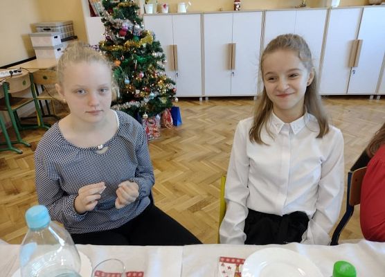 Uczennice siedzą przy wigilijnym stole.