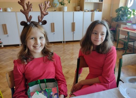 Uśmiechnięte uczennice siedzą przy wigilijnym stole.