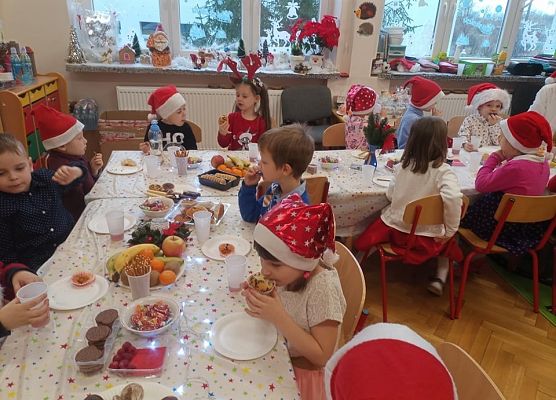 Dzieci siedzą przy stole podczas poczęstunku