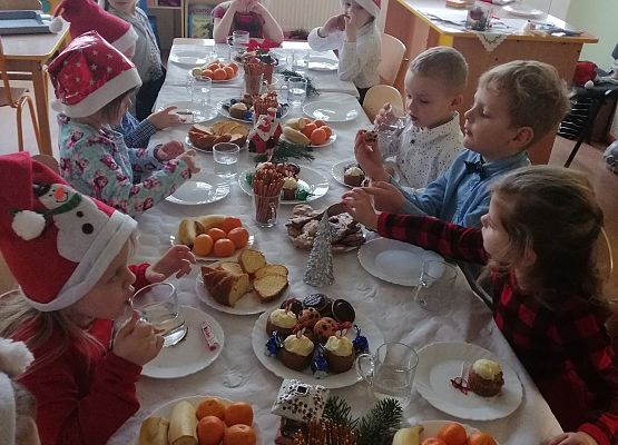 Dzieci siedzą przy wigilijnym stole