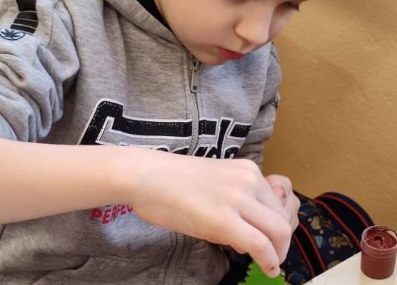 Uczeń maluje drewnianą choinkę