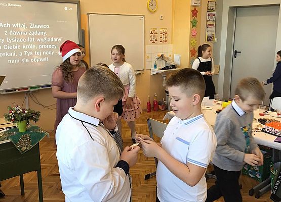 Uczniowie składają sobie życzenia łamiąc się opłatkiem.