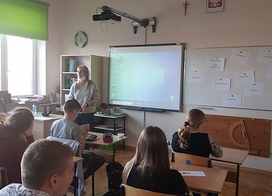 Uczniowie siedzą w ławkach i oglądają prezentację