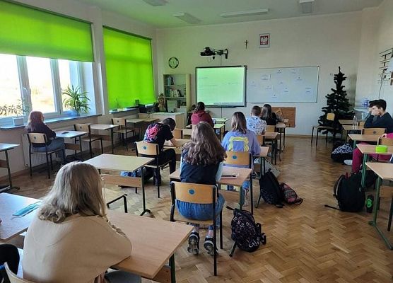 Uczniowie siedzą w ławkach i oglądają prezentację