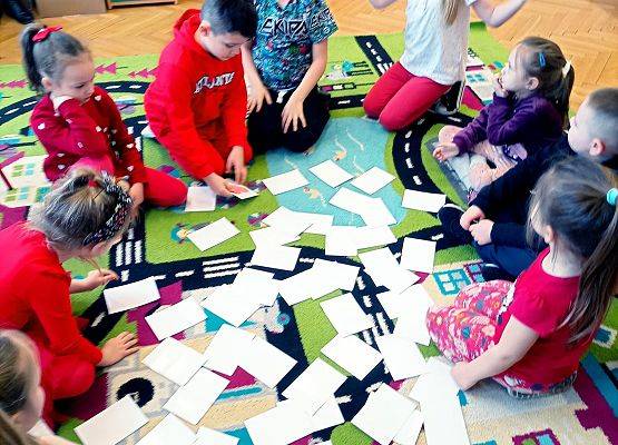 Dzieci układają domino na dywanie