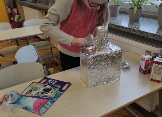 Uczennica przykleja elementy robota