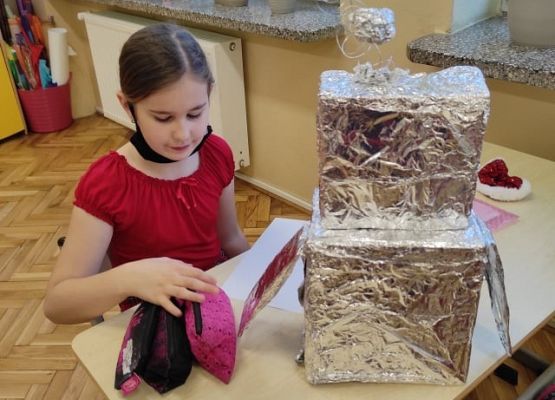 Uczennica przykleja elementy robota