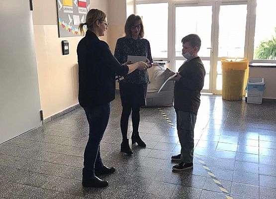 Pani wicedyrektor i pedagog wręczają uczniowi dyplom
