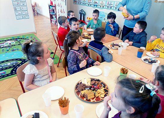 Dzieci siedzą przy stoliku podczas słodkiego poczęstunku