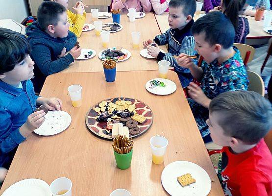 Dzieci siedzą przy stoliku podczas słodkiego poczęstunku