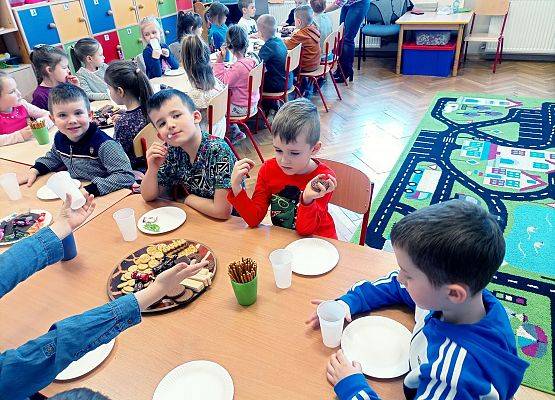 Dzieci siedzą przy stoliku podczas słodkiego poczęstunku