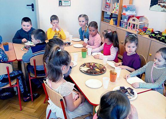 Dzieci siedzą przy stoliku podczas słodkiego poczęstunku