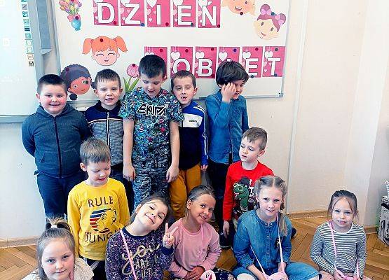 Dzieci pozują do zdjęcia na tle gazetki ściennej