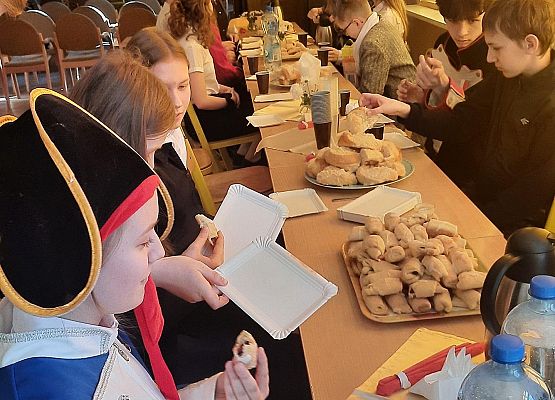 Uczniowie siedzą przy stoliku podczas słodkiego poczęstunku