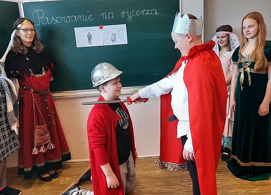 Uczniowie klasy V na lekcji historii odgrywają scenki z pasowania na rycerza