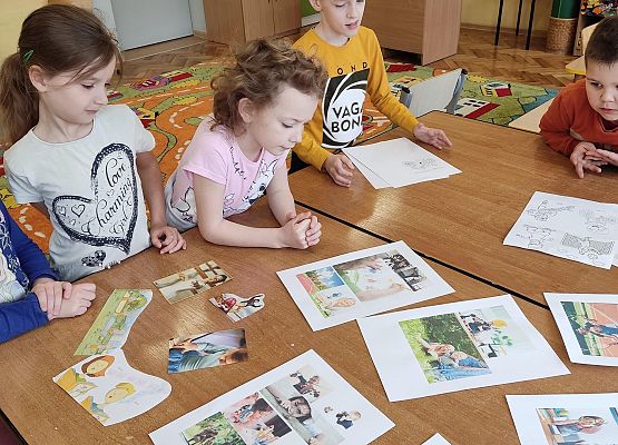 Uczniowie siedzą przy stole i pracują w grupe