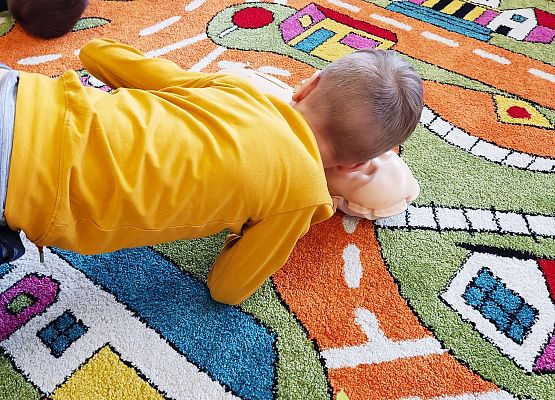 Chłopiec uczy się na fantomie reanimacji