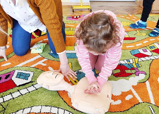 Dziewczynka uczy się na fantomie reanimacji