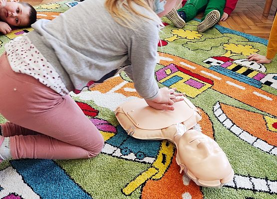 Dziewczynka uczy się na fantomie reanimacji