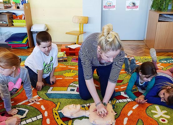 Nauczycielka pokazuje dzieciom, jak należy przeprowadzić reanimację
