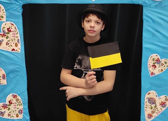 Uczeń stoi w ramce, na której są wzory kaszubskie.