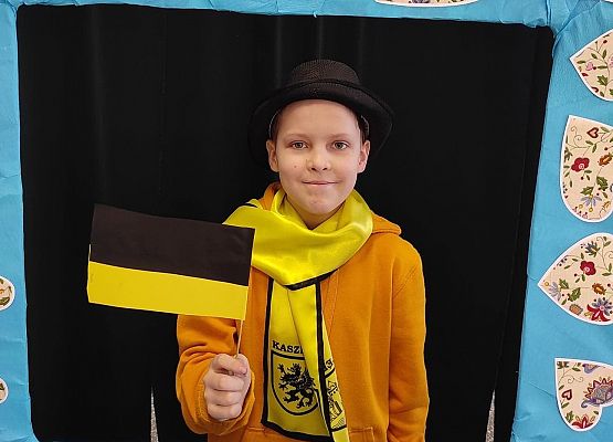 Uczeń stoi w ramce, na której są wzory kaszubskie.