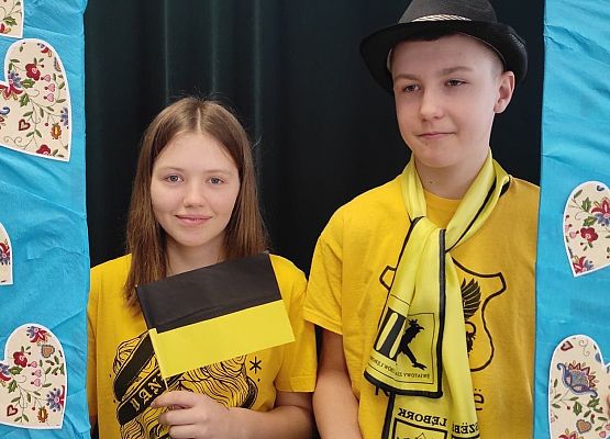 Uczniowie stoją w ramce, na której są wzory kaszubskie.