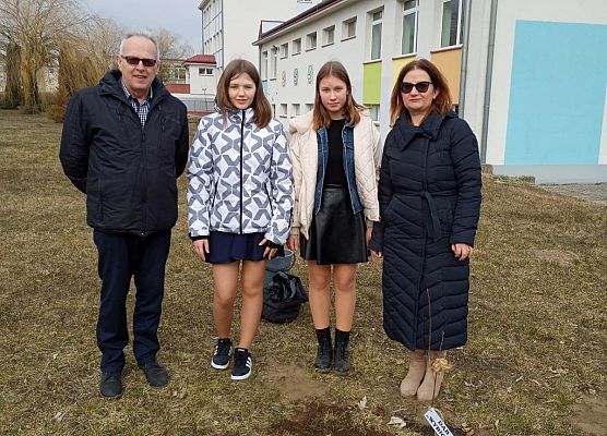 Przy posadzonym dębie  stoją: dyrektor, dwie uczennice i nauczycielka historii