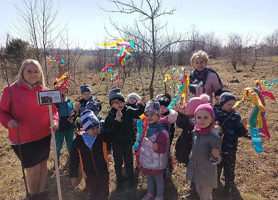 Dzieci idą w parach, w dłoniach trzymają gałązki ozdobione kolorowymi paskami bibuły