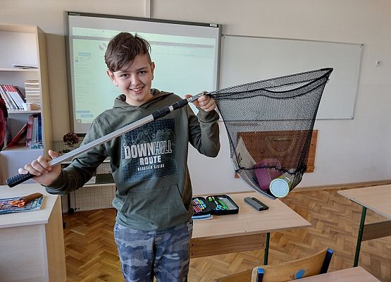 Uczeń prezentuje swoje książki w wędkarskim podbieraku
