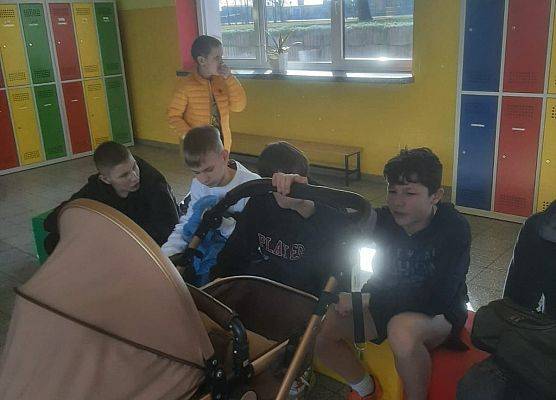 Uczeń prezentuje wózek dziecięcy, w którym przyniósł książki.