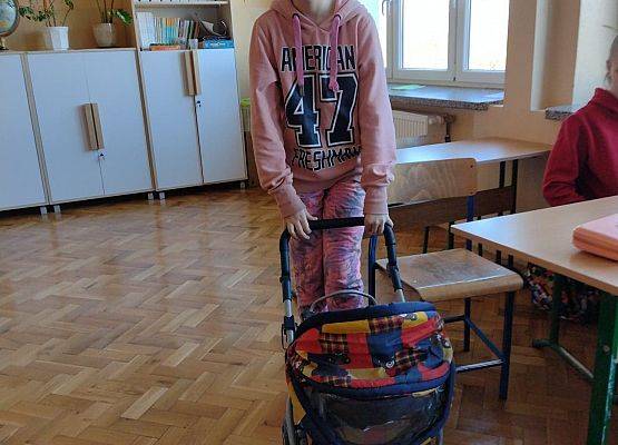 Uczennica prezentuje wózek dla lalek, w którym przyniosła książki