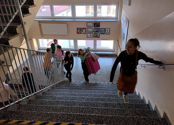 Uczniowie wchodzą po schodach bez plecaków.