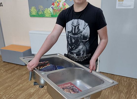 Uczeń prezentuje swoje książki w zlewozmywaku