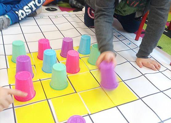 Dzieci kodują na macie z wykorzystaniem kolorowych kubków