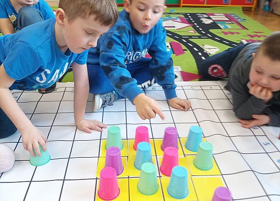 Dzieci kodują na macie z wykorzystaniem kolorowych kubków