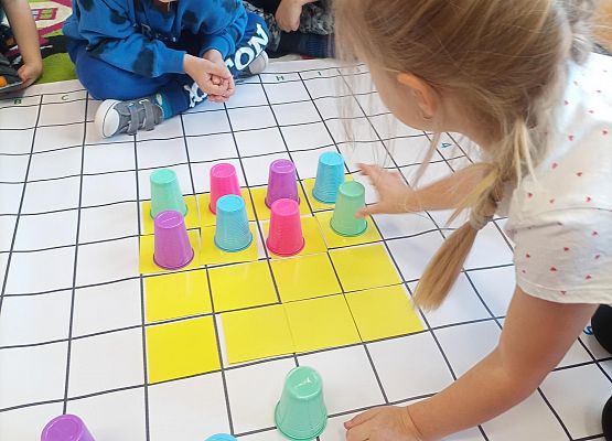 Dzieci kodują na macie sudoku z wykorzystaniem kolorowych kubków